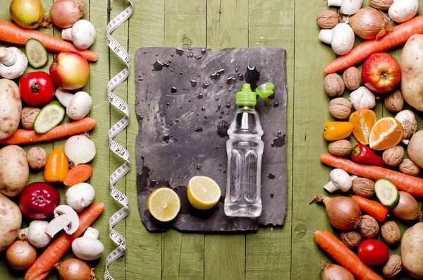 Gemüse und Obst, Wasserflasche auf Holzuntergrund und leeres Schneidebrett — Stockfoto
