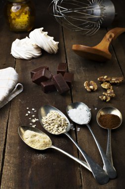 Kaşık şeker, kahve, yulaf ve beze, çikolata şekerleme, bal ve fındık gerçek kahverengi ahşap bir masa ile.