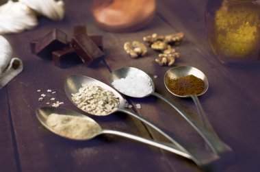 Kaşık şeker, kahve, yulaf ve beze, çikolata şekerleme, bal ve fındık gerçek kahverengi ahşap bir masa ile.