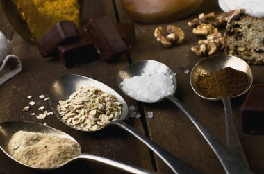 Kaşık şeker, kahve, yulaf ve beze, çikolata şekerleme, bal ve fındık gerçek kahverengi ahşap bir masa ile.