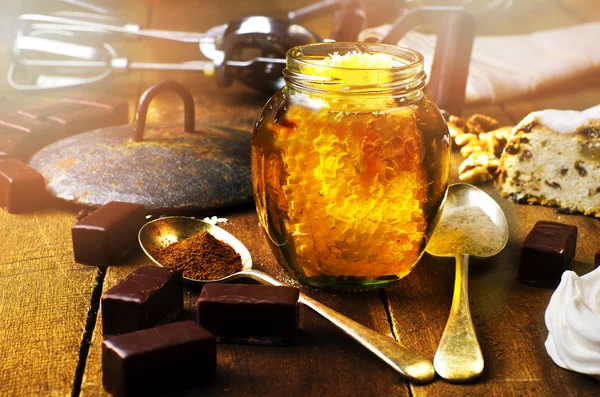 Jar of healthy real honey, chocolate marshmallow and fruit cake on real wooden table. — Stock Photo, Image