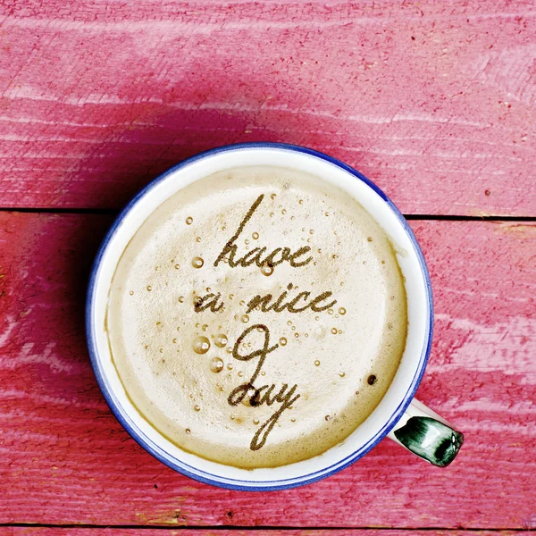Bir fincan kahve latte, cappuccino pembe ahşap masa üzerinde. Kahve köpüğü iyi günler formundan kelime var.