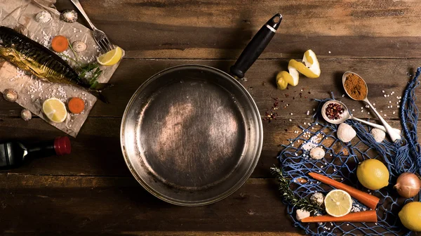 Cooking background. Smoked fish with spices and lemon on a wooden background. Maritime style, a blue fishing net and shells, top view.