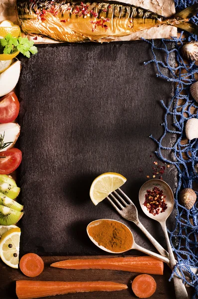 Kochhintergrund. Räucherfisch mit Gewürzen, Früchten und Zitrone auf einem schwarzen Stein. maritimer Stil, blaues Fischernetz und Muscheln, Draufsicht. Kopierraum. — Stockfoto