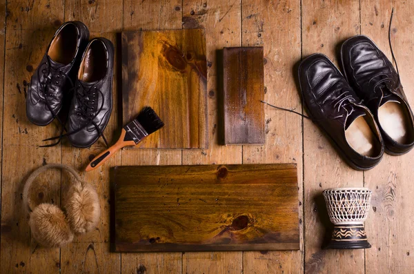 木製の床の背景にコピー スペースを持つ自然な木製の板。黒の靴、小さいドラム、居心地の良いイヤーマフの 2 つのペア. — ストック写真