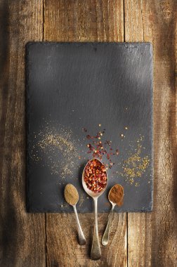 Siyah taş metal kaşık üzerinde yük arabası baharat. Ahşap arka plan. Biber, zencefil, tarçın.