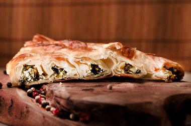 Ispanak ve peynirli börek, ahşap arka plan üzerinde Türk geleneksel yemek kadar haddelenmiş.