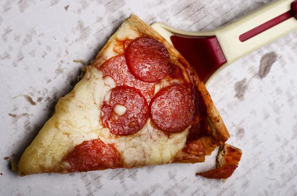 Dilim taze İtalyan klasik orijinal biberli Pizza ve pizza kesici yağ üzerinde beyaz karton lekeleri.
