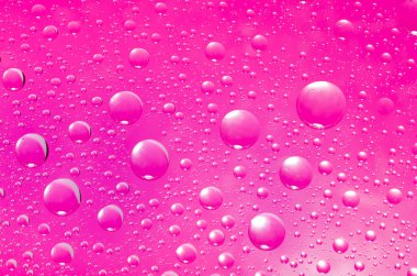 Su yakın çekim arka plan pembe yüzeye bırakır. Yansımalar onları ile cam üzerinde Su damlacıkları.