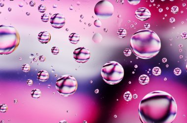 Su yakın çekim arka plan siyah, pembe ve beyaz cam yüzeyine düşer. Su damlacıkları ile onları yansımalar.