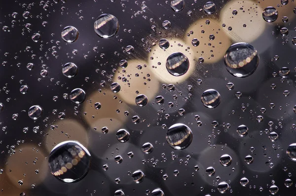 Close-up on water drops background on creamy and black surface. Water droplets on glass with reflections in them. — Stock Photo, Image