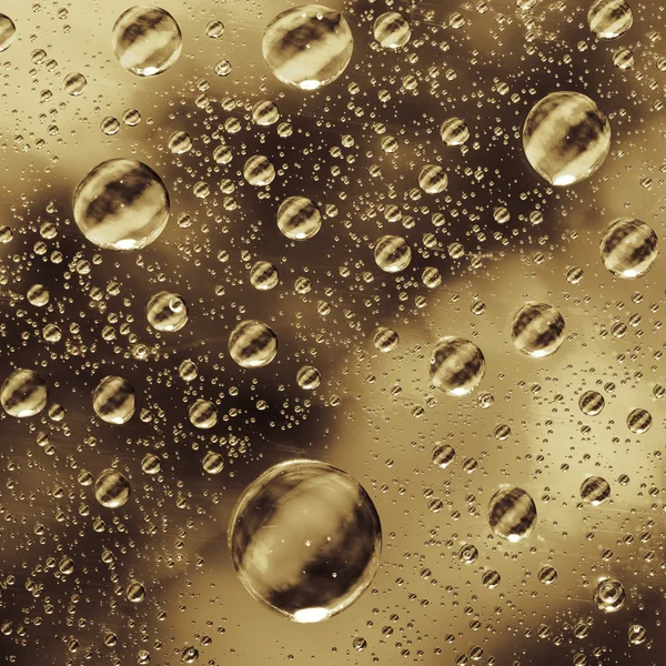 Close-up on water drops background on glass golden surface. Water droplets on glass with reflections in them. — Stock Photo, Image