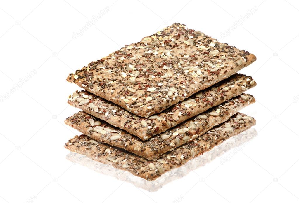 Stack of wholegrain crispy bread with sunflower, chia and sesames seeds on white background.