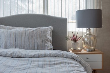 Yatak odasında ahşap masa üzerinde bitki vazo stiliyle klasik lamba