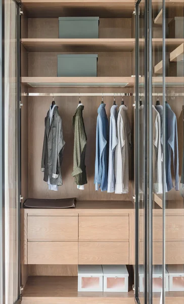 Shirts and suite hanging on rail in wooden wardrobe — Stock Photo, Image