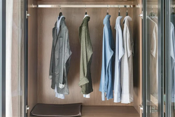 Shirts and suite hanging on rail in wooden wardrobe — Stock Photo, Image