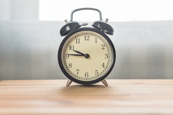Black alarm clock on wooden table — Stock Photo, Image