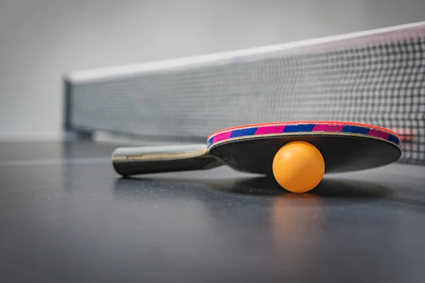 Table tennis racket with orange ball — Stock Photo, Image