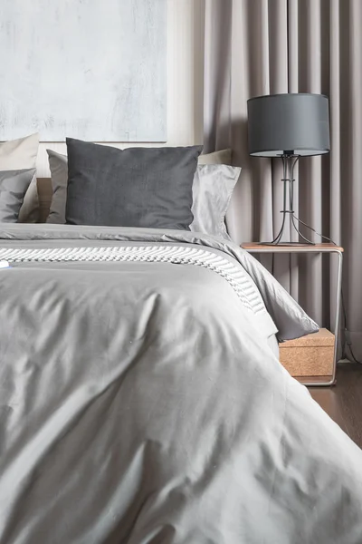 Grijs kussen op witte bed in moderne slaapkamer met zwarte lamp — Stockfoto