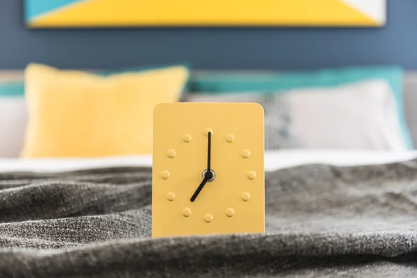 Modern yellow alarm clock design on bed — Stock Photo, Image