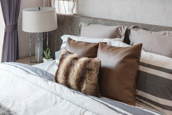 Brown pillows on bed with modern lamp — Stock Photo, Image