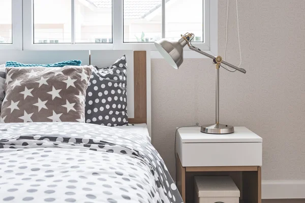 modern lamp on bedside table with wooden bed