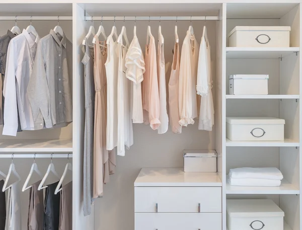 Kleider hängen in weißer Garderobe am Geländer lizenzfreie Stockfotos