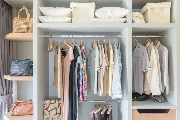 Clothes hanging on rail in wooden closet — Stock Photo, Image