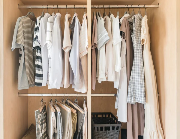 Clothes and dress hanging on rail in wooden closet — Stock Photo, Image