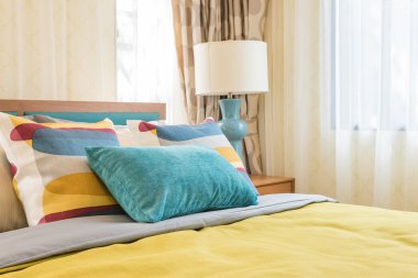 modern yatak odasında ahşap yatakta renkli yastıklar 