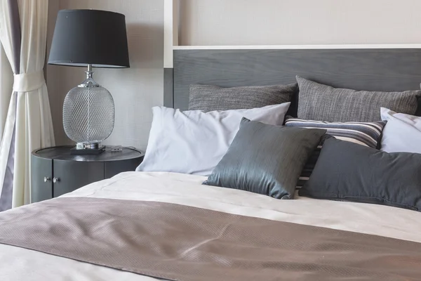 Kussens op bed en luxe zwarte lamp stijl aan houten tafel kant — Stockfoto