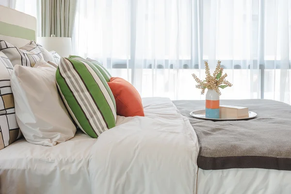 Almofadas coloridas na cama branca no quarto moderno — Fotografia de Stock