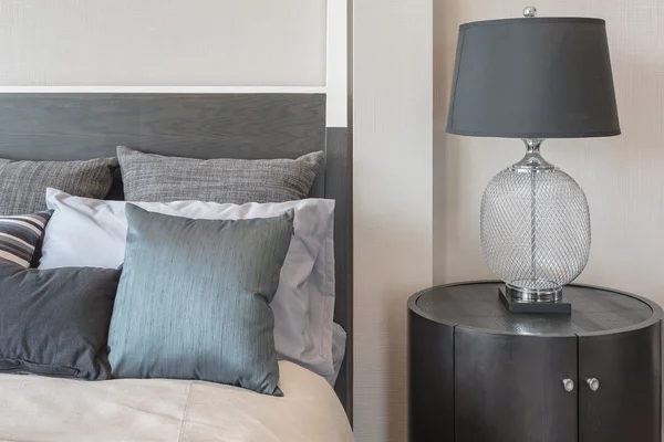 Almohadas en la cama y el estilo de lámpara negro de lujo en el lado de la mesa de madera — Foto de Stock