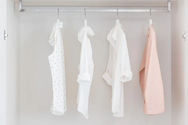 Shirts hanging on rail in white wooden wardrobe — Stock Photo, Image