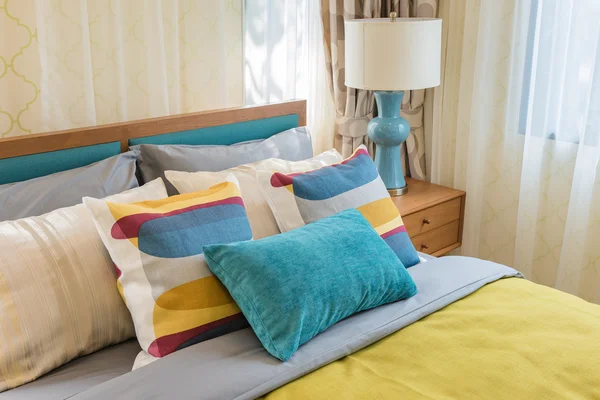 Bunte Kissen auf Holzbett im modernen Schlafzimmerdesign — Stockfoto