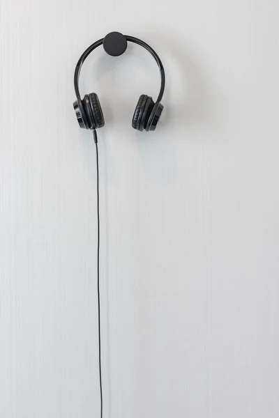Modernes schwarzes Kopfhörer hängt an weißer Wand — Stockfoto