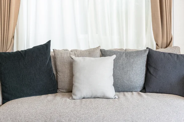 Set of pillows on modern sofa with white curtain — Stock Photo, Image