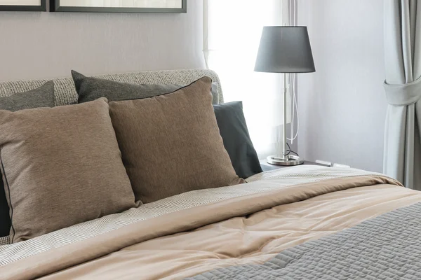 Almohadas marrones en la cama con lámpara negra en dormitorio moderno —  Fotos de Stock