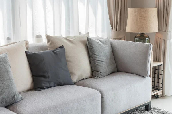 Modern grey sofa with pillows and modern lamp on table side in l — Stock Photo, Image