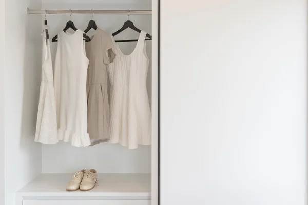 Jordnära färg klänning hänger på järnväg i vit garderob med vi — Stockfoto