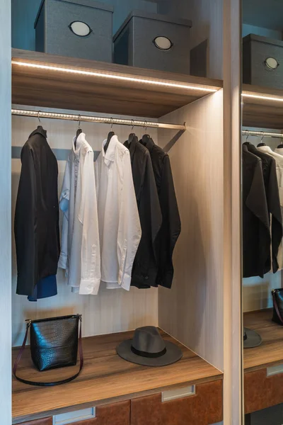 レールに掛けられた服のセットと現代的なワードローブ 近代的なクローゼットのインテリアデザインコンセプト ストック写真