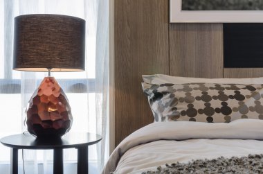 Yatak odasında yuvarlak masa üzerinde kahverengi lamba