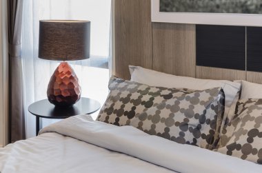 Yatak odasında ahşap yuvarlak masa üzerinde kahverengi lamba