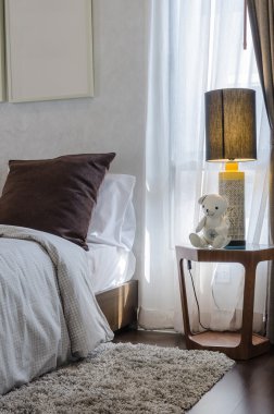 ahşap masa ve lamba yatak üzerinde kahverengi yastık 