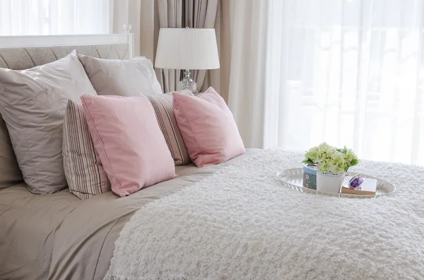 Cuscini rosa sul letto con vassoio bianco di fiori — Foto Stock