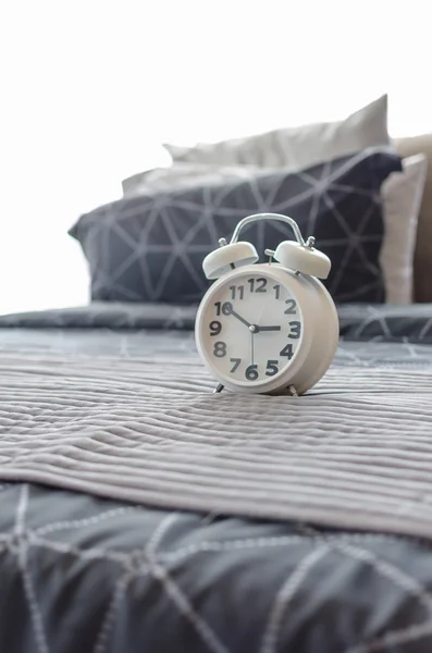 White alarm clock on bed — Stock Photo, Image