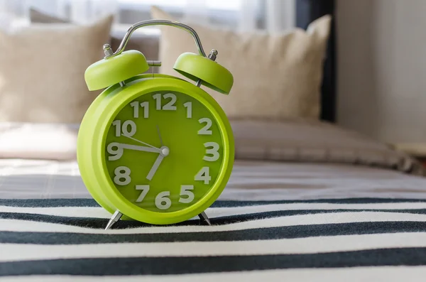 Modern green alarm clock on bed — Stock Photo, Image