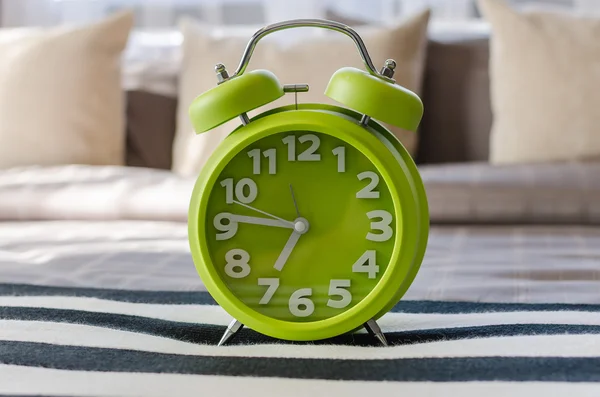 Modern green alarm clock on bed — Stock Photo, Image