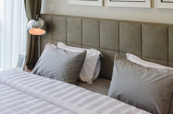 Grey pillows on bed with modern lamp — Stock Photo, Image