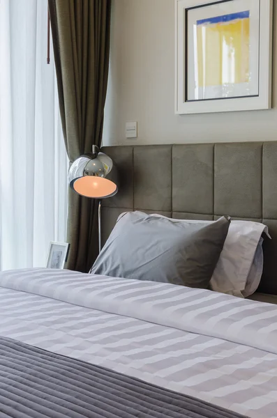 Travesseiro cinza na cama com lâmpada moderna — Fotografia de Stock